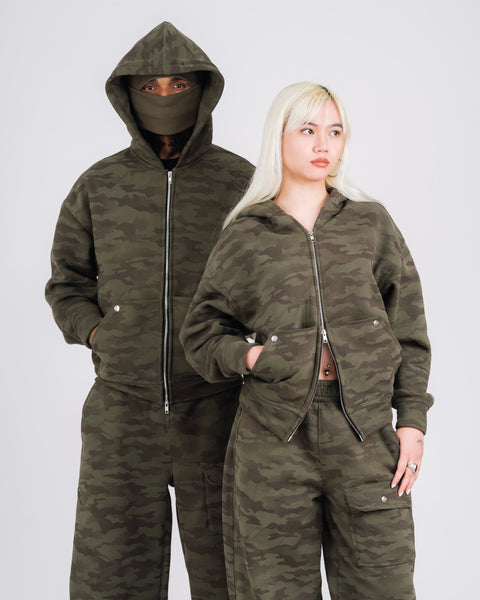 Two people wearing matching camouflage outfits on a white background